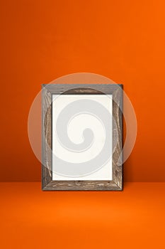 Wooden picture frame leaning on an orange wall