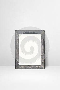 Wooden picture frame leaning on a white wall