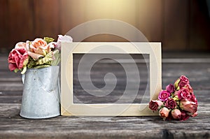 Wooden picture frame with rose paper flower in tinpot over blurred wood background