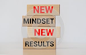 Wooden pieces on a wooden background showing the words new mindset and new results