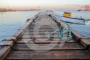 Wooden pier with blue sea. Wood floor or terrace beside the blue crystal clear sea, boat and a rope.