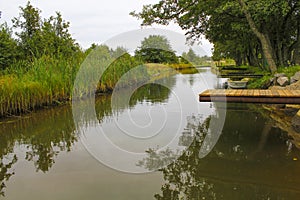 A wooden pier bridge over a river that goes into the distance along the reeds. A scene of calm pacified village life photo