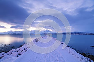 Wooden pier covered in snow, beautiful mountain on background, Tromso, Norway