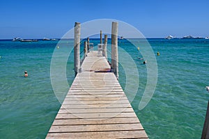 Wooden pier and crystal clear blue water of legendary Pampelonne beach near Saint-Tropez, summer vacation on French Riviera,