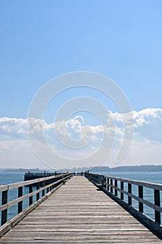 Wooden pier extending into ocean, hazy blue sky