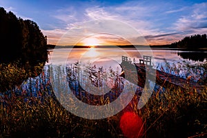 Wooden pier with fishing boat at sunset on a lake in Finland