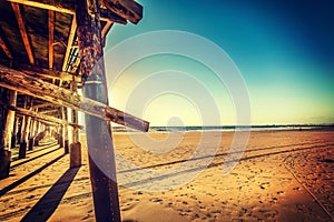 Wooden pier and golden sand in Newport Beach at sunset