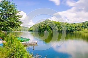 Wooden pier or jetty and a boat on lake sunset and sky reflection water.