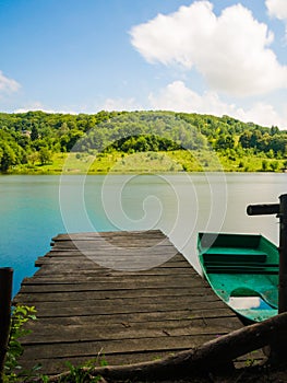 Wooden pier or jetty and a boat on lake sunset and sky reflection water.