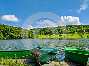 Wooden pier or jetty and a boat on lake sunset and sky reflection water.