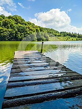 Wooden pier or jetty and a boat on lake sunset and sky reflection water.