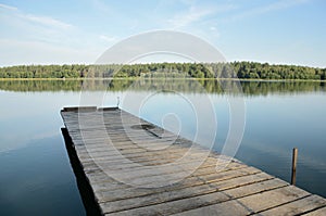 Wooden pier on lake in afternoon in windless weather