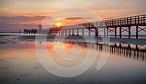 De madera muelle jefe de sobre el faro sobre el amanecer en, Playa 