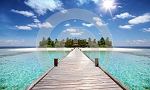 A wooden pier leading to a tropical paradise island