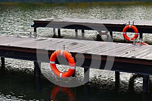 Wooden pier with lifebuoys. Autumn cozy water landscape with a pier for boats