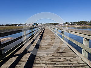 The wooden pier looking inwards at at Murrell\'s Inlet, south of Myrtle Beach, South Carolina, USA, on a sunny day with blue