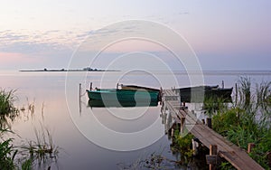 Wooden Pier with Moored Boats on the Lake During Dawn