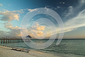 Wooden pier over sea water against the background of the sky during sunset