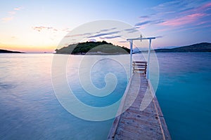 Wooden pier on paradise beach in Ksamil during sunset in Albania