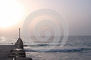 Wooden pier with pillars on the summer twilight beach