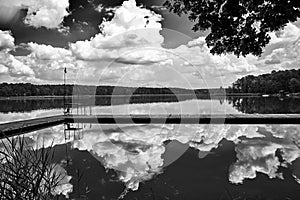 Wooden pier and reflection of clouds in the waters of Lake Chycina