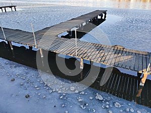 Wooden pier on a river covered with ice in winter