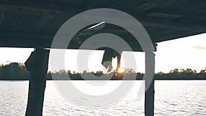 Wooden pier on the river in the setting sun, girl`s legs