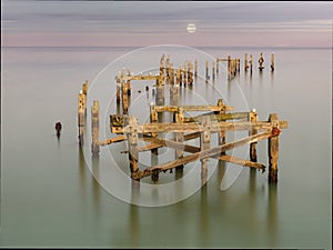 Wooden pier ruins with moon in background