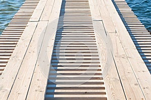 Wooden pier in the sea close-up with clear blue water under it.