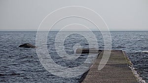 Wooden pier in the sea or lake. Calm and small waves.