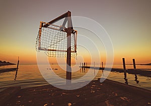 Wooden pier by the sea, sunset at water, orange sky