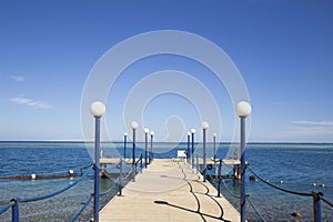 Wooden pier with street lights, fenced with iron ropes on the sh