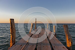 Wooden pier at the sunset. Evening sky over sea with footbridge. Calm evening landscape. Empty pier at seaside with copy scape.