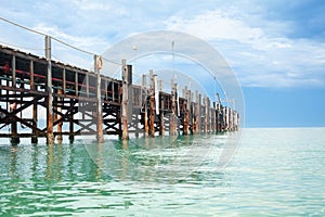 Wooden pier on turquoise water, blue sky, clouds background, ship wharf scenic perspective view seascape, fishing boat dock, quay