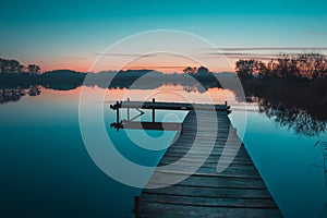 Wooden pier and a view of a calm lake after sunset