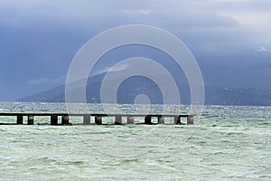 Wooden pier with waves on Lago di Garda Sirmione, Italy