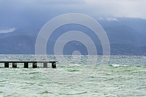 Wooden pier with waves on Lago di Garda Sirmione, Italy
