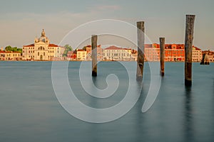 Wooden pilings on the water's surface with beautiful buildings in the background. Venice, Italy.