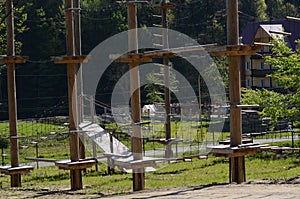 Wooden pillars and hanging ropes of a rope park on the background of green forest in the Carpathians. Ukraine