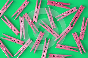 Wooden pink-crimson clothespins are scattered on a cyan-green background. Frame of clothespins. View from above. Copy space. Flat