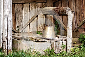 Wooden plank shelter for the water well site with a bucket