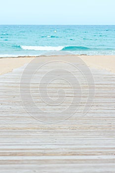 Wooden Plank Walkway on the Beach with White Sand Turquoise Sea with Waves and Blue Sky. Idyllic Seascape. Summer Vacation