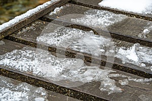 Wooden planks of bridge with ice as background. Trail froze after snowfall