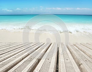 Wooden planks decking on the tropical white sandy beach and blue sea blurred background