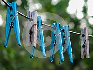 Wooden and plastic clothespins hanging from a wire