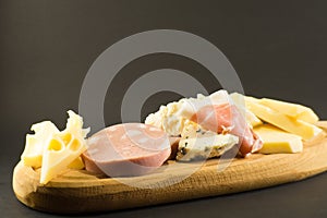 wooden plate with cheeses and cold cuts like gruyere, mortadella, Roquefort and prosciutto