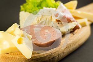 wooden plate with cheeses and cold cuts like gruyere, mortadella, Roquefort and prosciutto