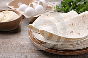 Wooden plate with corn tortillas on table. Unleavened bread