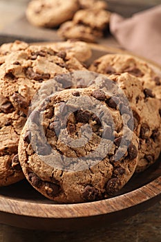 Wooden plate with delicious chocolate chip cookies, closeup