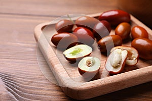 Wooden plate with fresh Ziziphus jujuba fruits on table, closeup